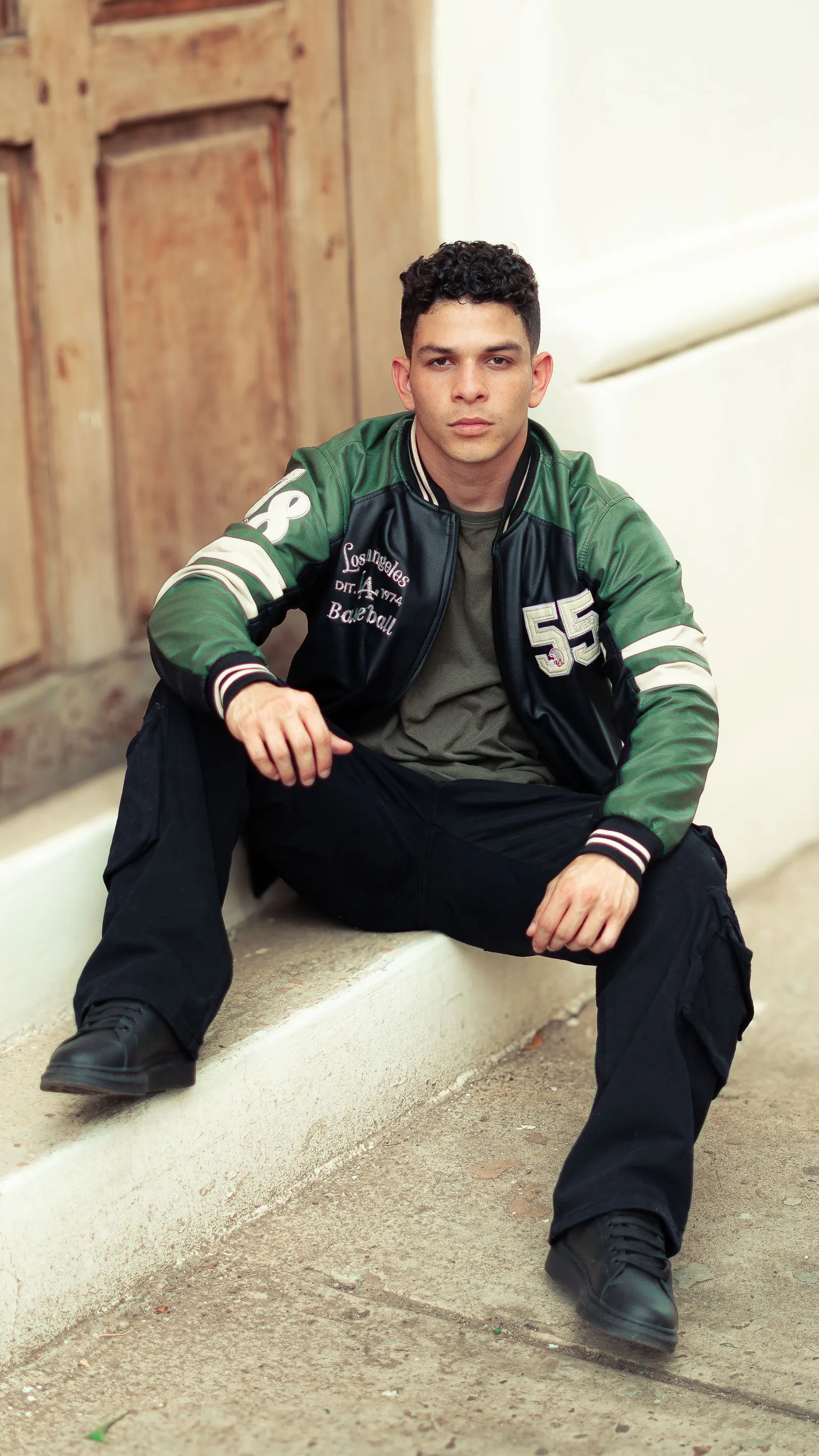 Hombre con campera varsity verde y pantalón cargo negro
